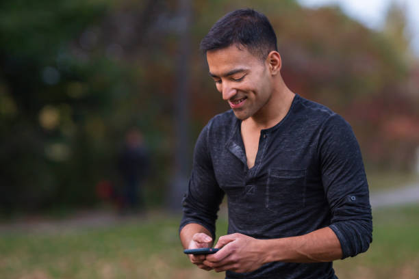 istock Attractive Indian man texting on mobile phone 1220669682