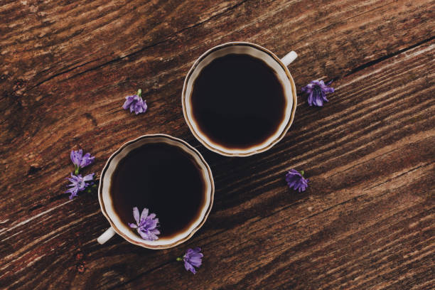 Lilac chicory flowers and cups on vintage wooden table. Flat lay, copy space. Natural coffee substitute.