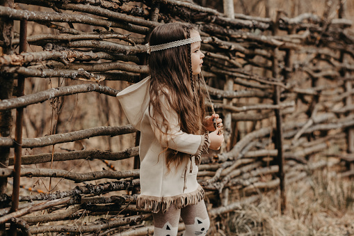 Fashion outdoor portrait of girl with long hair in bohemian style. Soft warm vintage color tone. Hippies, ethnicity, boho baby, Indians, feather decoration.