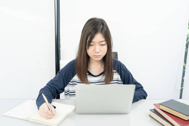 istock Young female student  sitting in living room and learning online 1220679999
