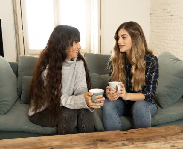 istock COVID-19 lockdown. Confident and optimistic women girlfriends together talking and drinking hot drink staying together at home in isolation. Stay home Stay safe health and safety campaign concept. 1220681009