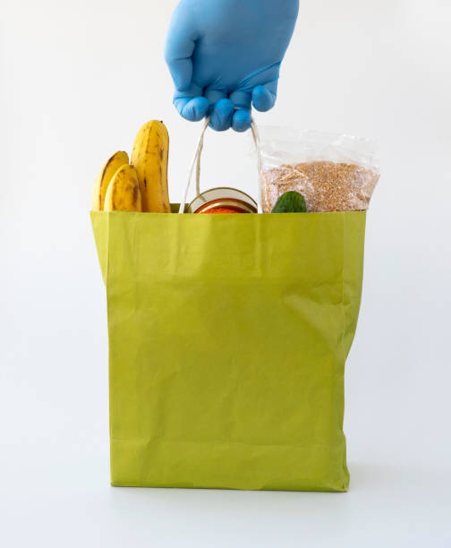 saco de papel usando luva azul. entrega de alimentos durante o período de quarentena coronavírus covid-19. modo de auto-isolamento durante uma pandemia, fique em casa. entrega de alimentos vitais.  espaço de cópia - supermarket fast food fast food restaurant people - fotografias e filmes do acervo