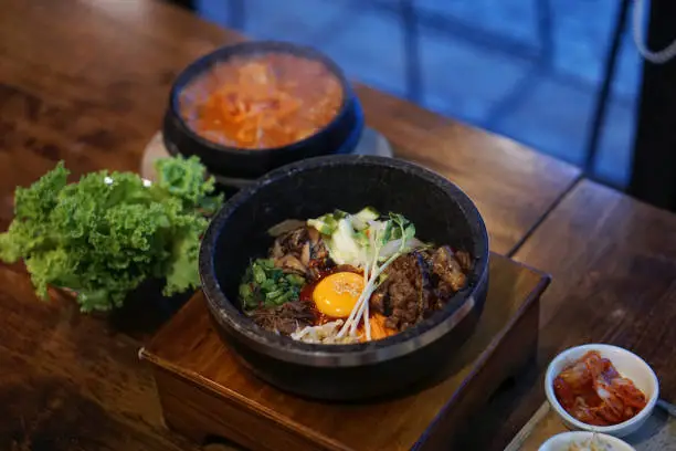 Photo of Dolsot bibimbap - Korean mixed rice, Include steamed rice, vegetables, pork and fried egg on top, served in a hot stone pot.