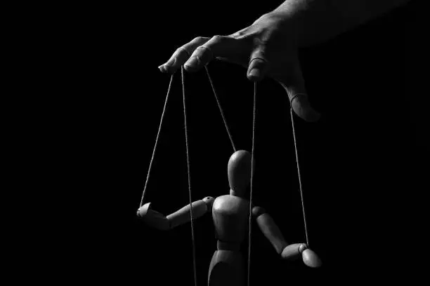 Photo of Conceptual image of a hand with strings on fingers to control a marionette in monochrome