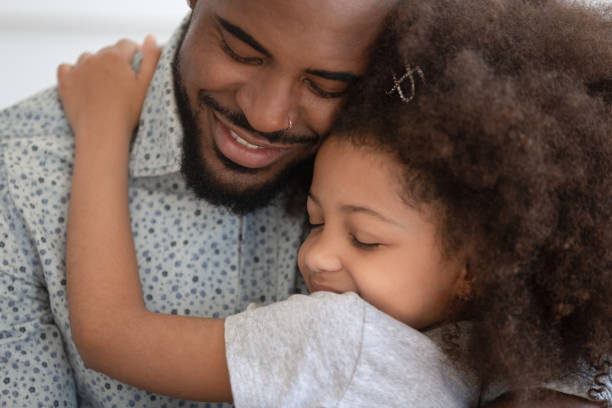 amorevole papà afroamericano abbraccia figlia piccola - male smiling african descent black foto e immagini stock