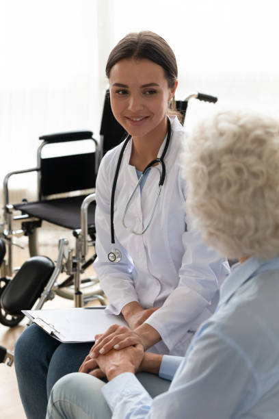 istock Friendly doctor supporting disabled patient during visit, holding hand 1220704575