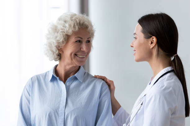 istock Caring nurse touching smiling older woman shoulder, expressing support 1220704624