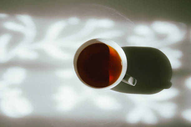 istock White cup of tea on abstract background of natural curtain shadow falling on white table. Black and white monochrome tone 1220704627