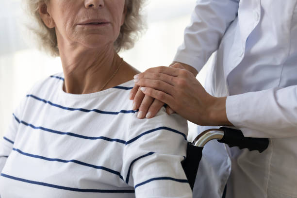 istock Caregiver supporting disabled older woman, holding hands on shoulder 1220704654