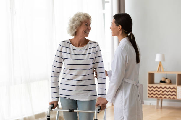 istock Friendly caregiver helping smiling disabled older woman with walker 1220704668