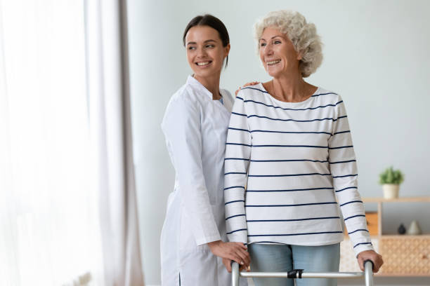 istock Smiling caregiver supporting older woman standing with walker 1220704689