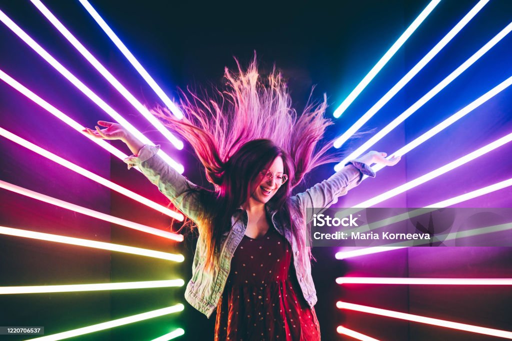dancing girl Attractive dancing girl, hair flying, neon light. Portrait of girl posing with hands up. Party - Social Event Stock Photo