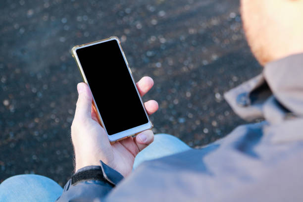 istock sitting man's hand holding smartphone with blank screen 1220707795