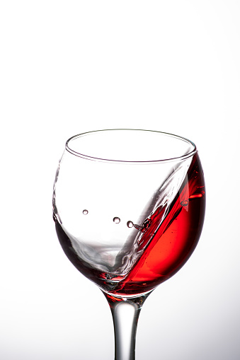 drop falling into a glass with red wine and a splash at an amazing angle