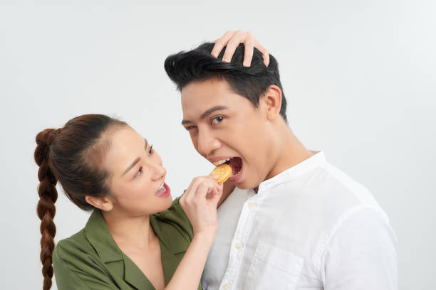 istock Gorgeous fun couple feeding eachother cookies over white 1220708127