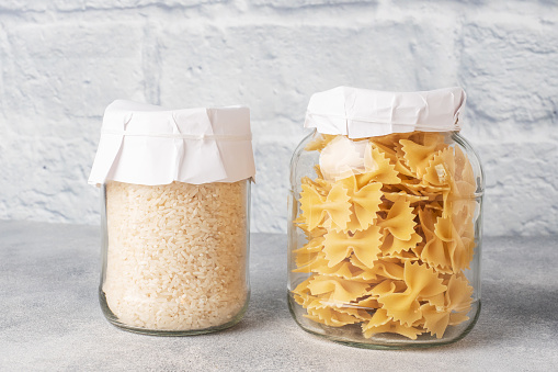 Dry pasta and rice in a glass jar. Copy space. Concept of food storage, donations
