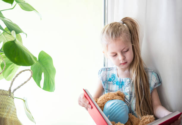 istock Sad child girl by the window 1220708915