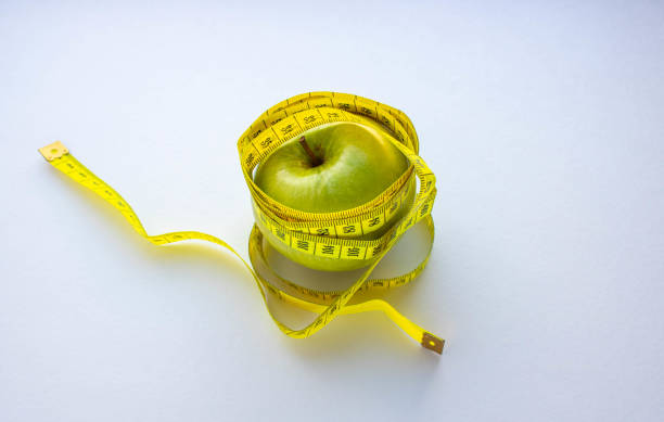 istock an Apple and a centimeter-long ribbon on a white background with a place to insert text. minimalism. concept of diet, healthy eating, fat burning, calories. 1220709005