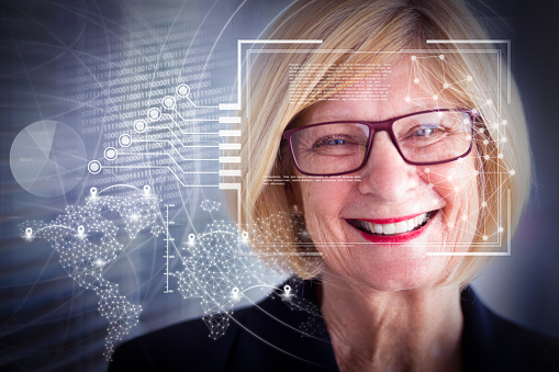 Joyful senior business lady and virtual identification graphics. Closeup portrait of smiling attractive businesswoman looking at camera in office with jalousie in background. Front view.