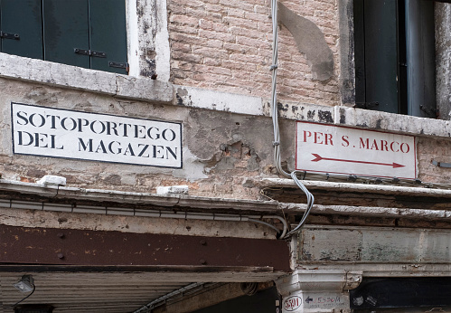 Venice, Italy - June 30, 2017: A view of dilapidated facades of the houses with signs. Text means for s.Marco and Soto portego of the magazen in Venice, Italy.
