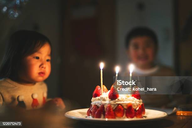 誕生日ケーキの前に座っている兄弟姉妹