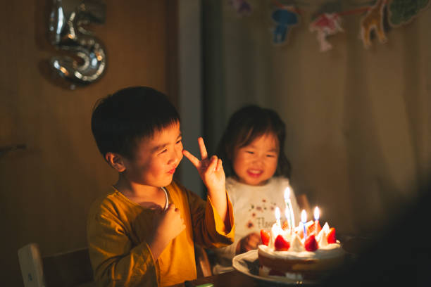 誕生日ケーキの前に座っている兄弟姉妹 - 日本 写真 ストックフォトと画像