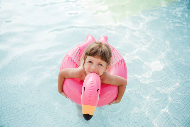 szczęśliwa dziewczynka pływa z gumowym flamingiem w basenie. - inflatable ring obrazy zdjęcia i obrazy z banku zdjęć