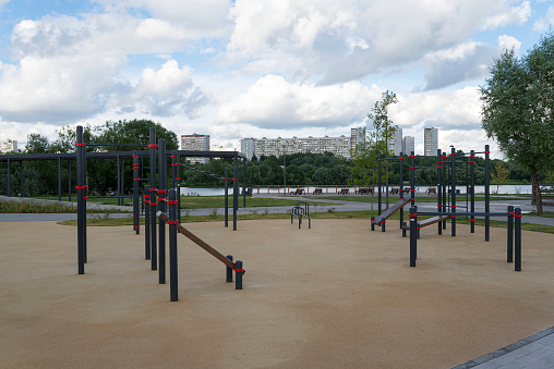 Playground with horizontal bars in the open air on the background of the river and houses.