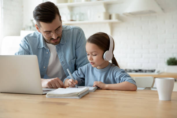 Caring dad and daughter have online video class at home