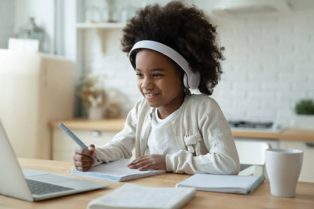 garota biracial sorridente assistir vídeo em laptop em casa - home schooling audio - fotografias e filmes do acervo
