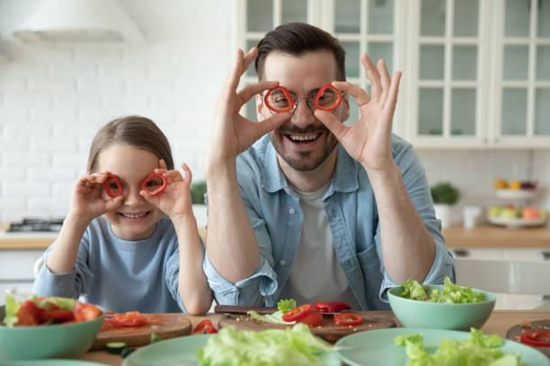 Smiling young dad and little daughter have fun cooking together