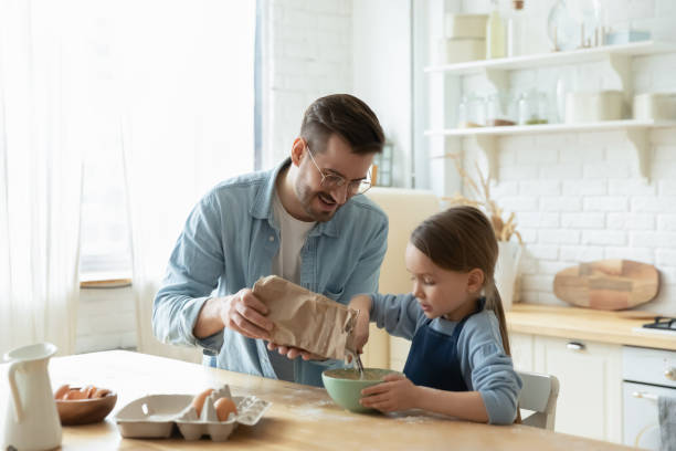 troskliwy tata i mała córka pieczenia w kuchni razem - baking food cookie breakfast zdjęcia i obrazy z banku zdjęć