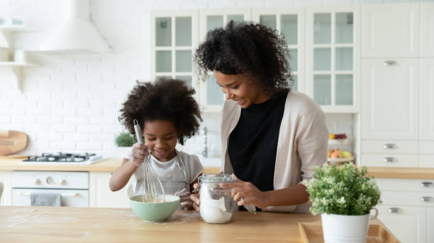 Happy biracial mom and daughter bake in kitchen together