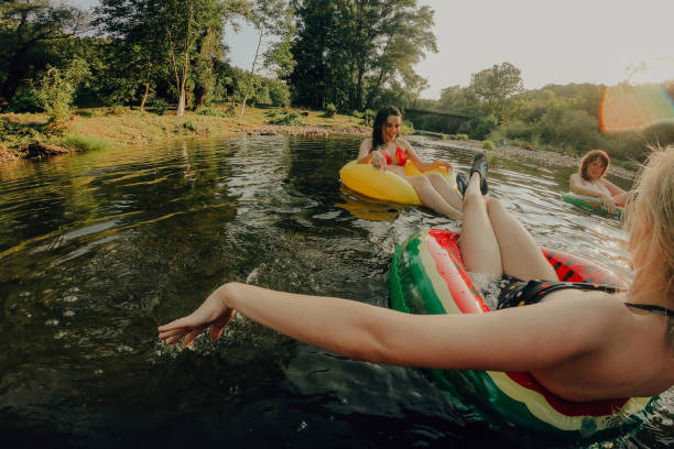 Relaxing on inflatable rings in the river Photo of girlfriends relaxing on inflatable rings in the river inner tube stock pictures, royalty-free photos & images