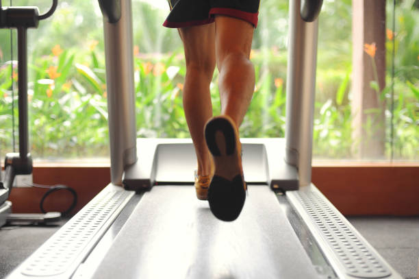Sportspeople running on treadmill in gym on sunny day