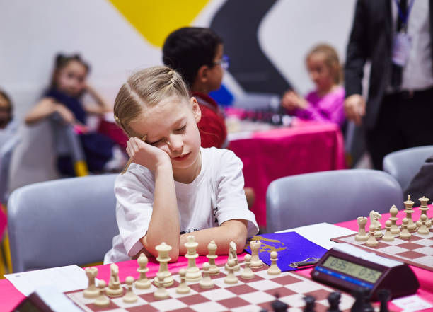 Small cute girl infront of chess board on chess tournament look very bored stock photo