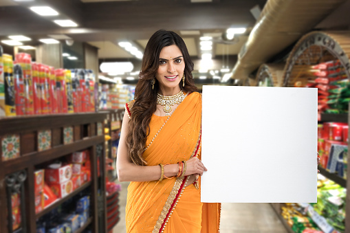 Excited woman holding placard in grocery of supermarket