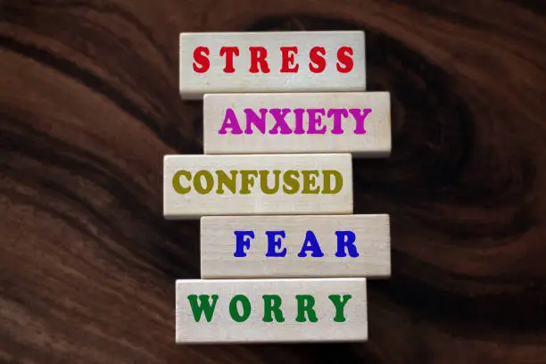 Photo of Mental health awarness concept with single words printed on wooden blocks - stress, anxiety, confused, fear, worry and all negativity.