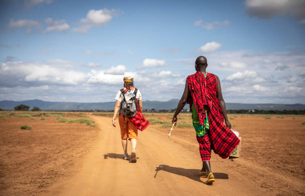 hikers walking on a dusty road in a maasai land in Tanzania stock photo