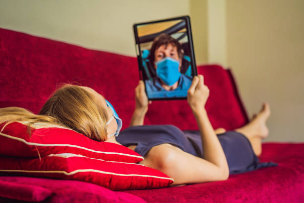 istock Coronavirus. Woman and man in quarantine for coronavirus wearing protective mask. Working from home and using video call. Video conference 1220728734
