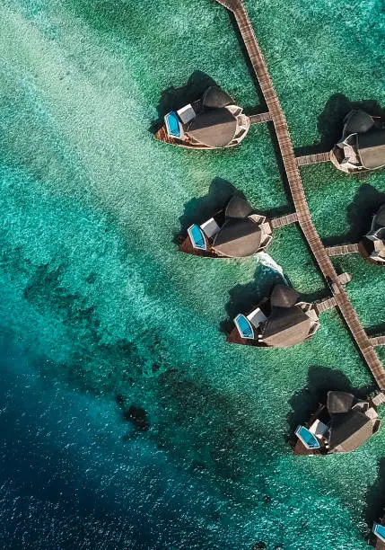 Maldives Island Resort Lagoon with Water Villas from above. Luxurious Over Water Villas are typical for the Maldives.