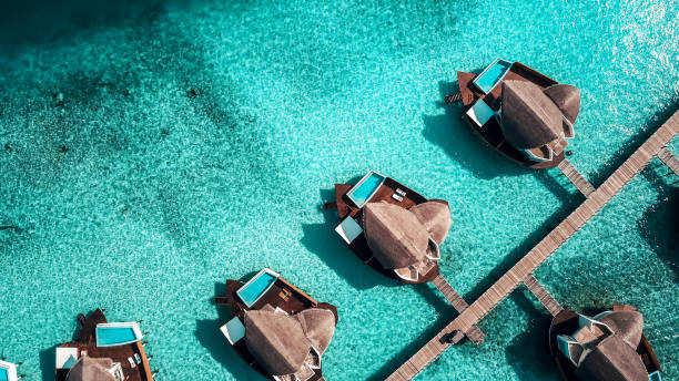 Maldives Island Resort Over Water Villas Luxurious Maldives Island Resort Water Villas from above. Over Water Villas are typical for Maldives resorts jetty aerial stock pictures, royalty-free photos & images