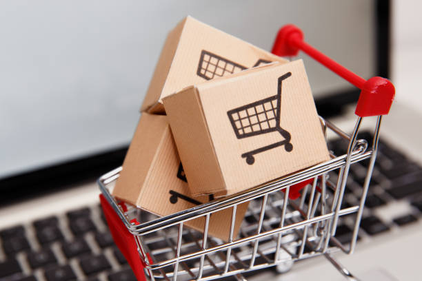 paper boxes in a shopping cart on a laptop keyboard. Concepts about online shopping that consumers can buy things directly from their home or office just using a few clicks via web browser. muchas cajas de papel en un pequeño carro de la compra en un teclado de portátil. conceptos sobre compras en línea que los consumidores pueden comprar cosas directamente desde su casa u oficina con solo unos pocos clics a través del navegador web.
