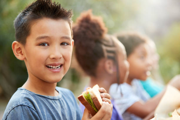 시골의 야외 테이블에서 건강한 피크닉을 먹는 친구들과 소년의 초상화 - apple eating healthy eating friendship 뉴스 사진 이미지