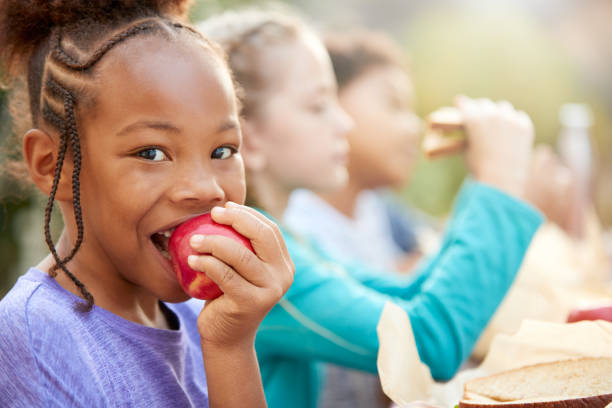 시골의 야외 테이블에서 건강한 피크닉을 먹는 친구와 소녀의 초상화 - child eating apple fruit 뉴스 사진 이미지