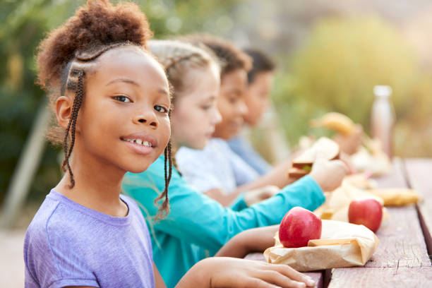 시골의 야외 테이블에서 건강한 피크닉을 먹는 친구와 소녀의 초상화 - apple eating healthy eating friendship 뉴스 사진 이미지