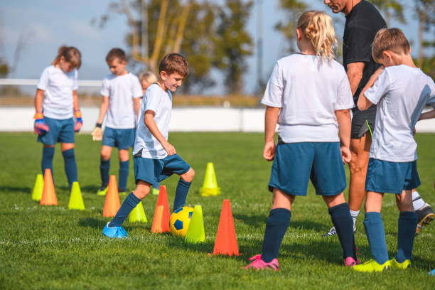 istock Teammates Watching as Boy Footballer Does Dribble Drill 1220731651