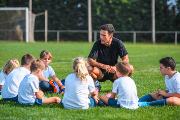 istock Coach Talking With Young Footballers Sitting on Field 1220731655