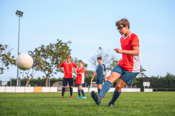 istock Red Jersey 14 Year Old Footballer Practicing on Field 1220731669