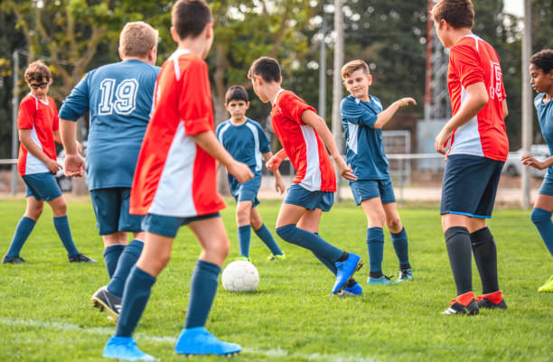 istock Red and Blue Jersey Boy Footballers Competing for Control 1220731690